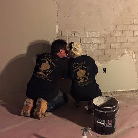 Two men are working on a wall.