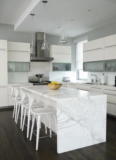 A kitchen with white cabinets and marble counter tops.